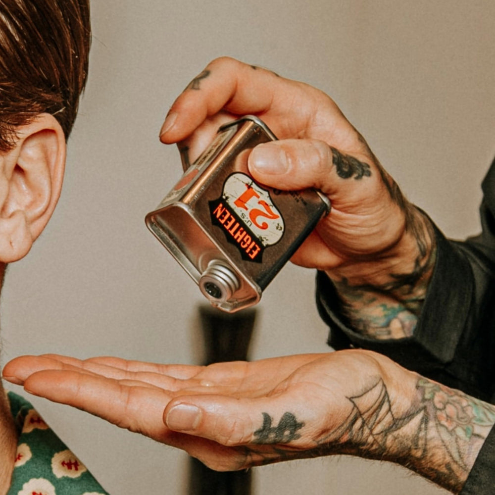 18.21 Man Made bottle beside tattooed forearm, showing enhanced tattoo vibrancy benefit