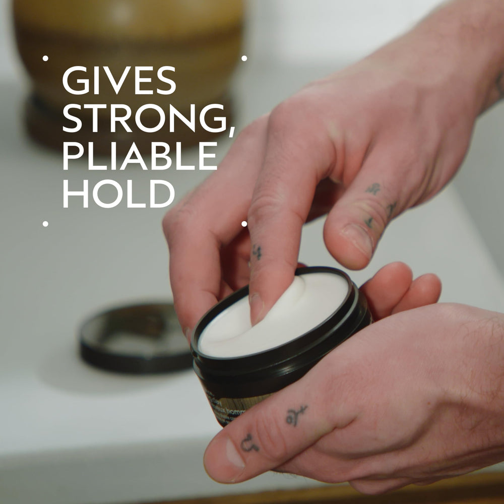 Open jar close‑up of Aveda clay texture showing matte, spreadable consistency for styling