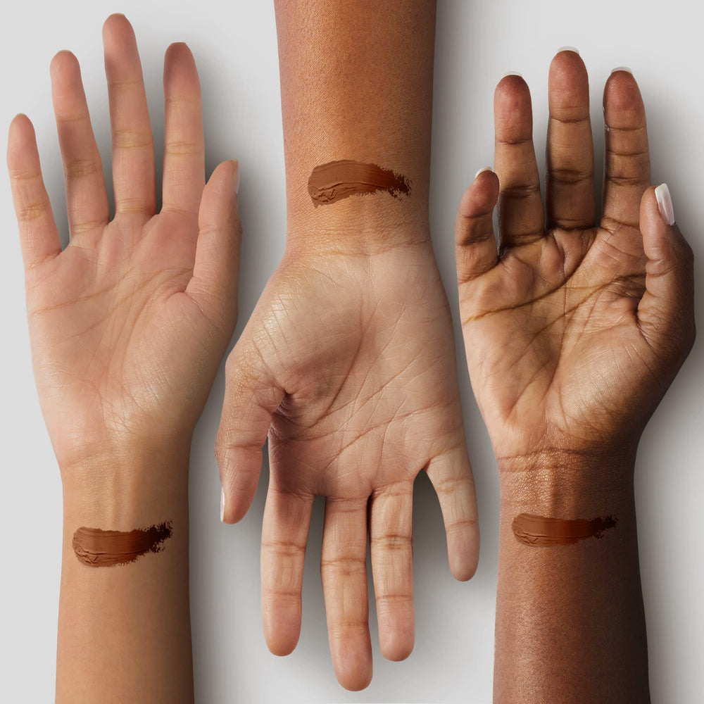 Black Radiance foundation stick held in hand to show compact scale and travel-friendliness
