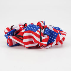 briutn scrunchie next to hand and coin illustrating compact size and portability