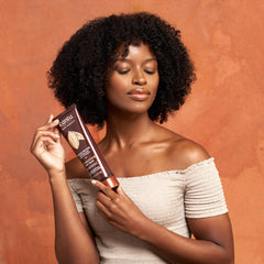 Open tub of Cantu cream with finger applying, showing easy spreadability benefit