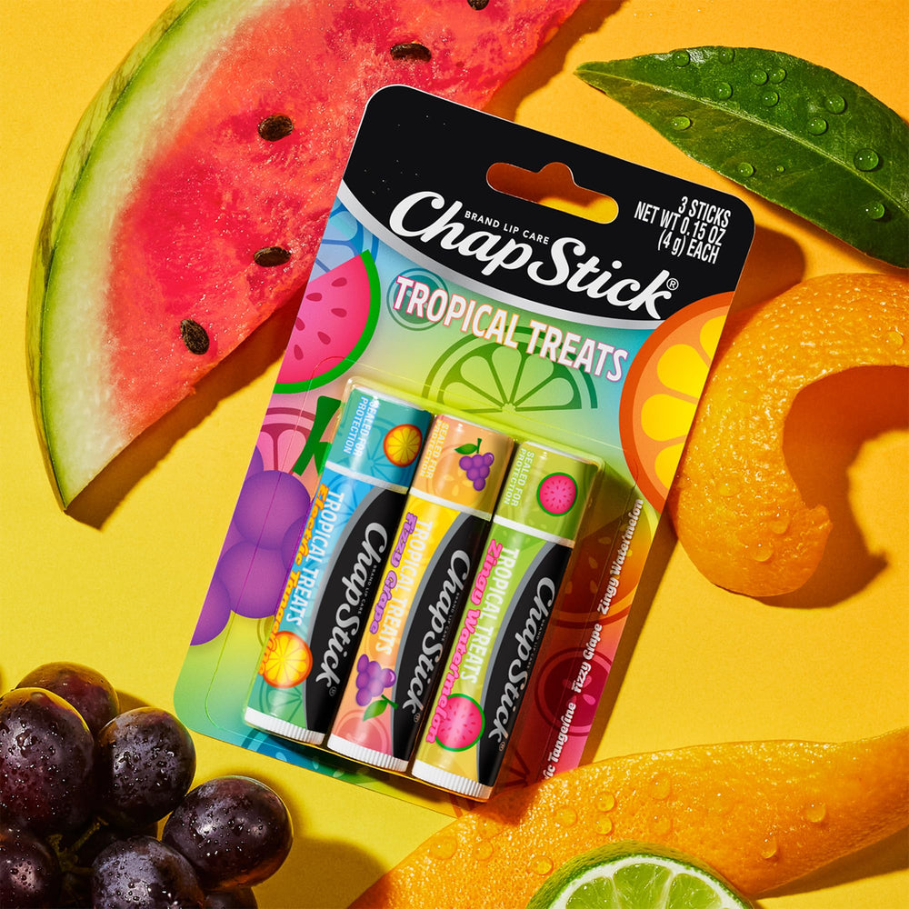 ChapStick by sunglasses on sand conveying travel-ready lip protection