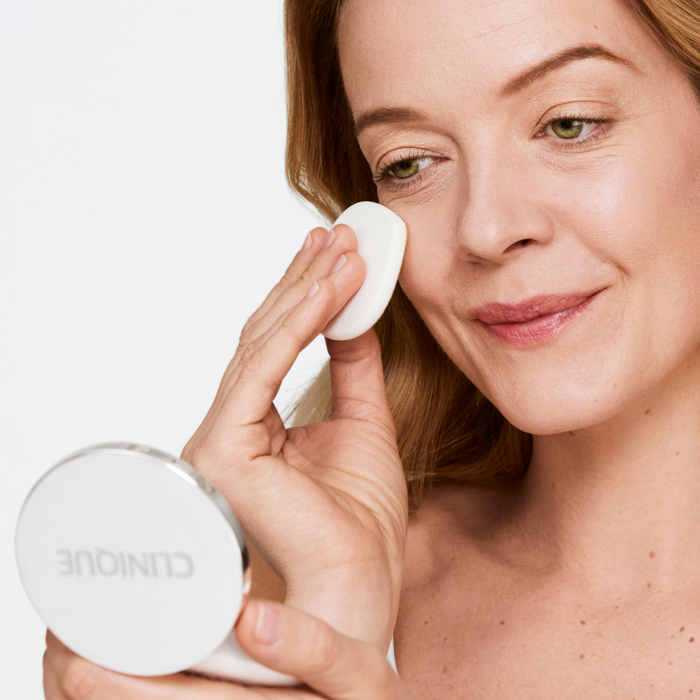 Hand holding Clinique compact to show size and easy on-the-go benefit
