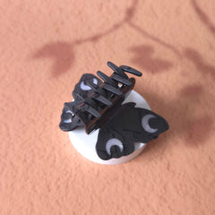 Clip Sugar butterfly clip next to a hand for scale demonstrating compact portability