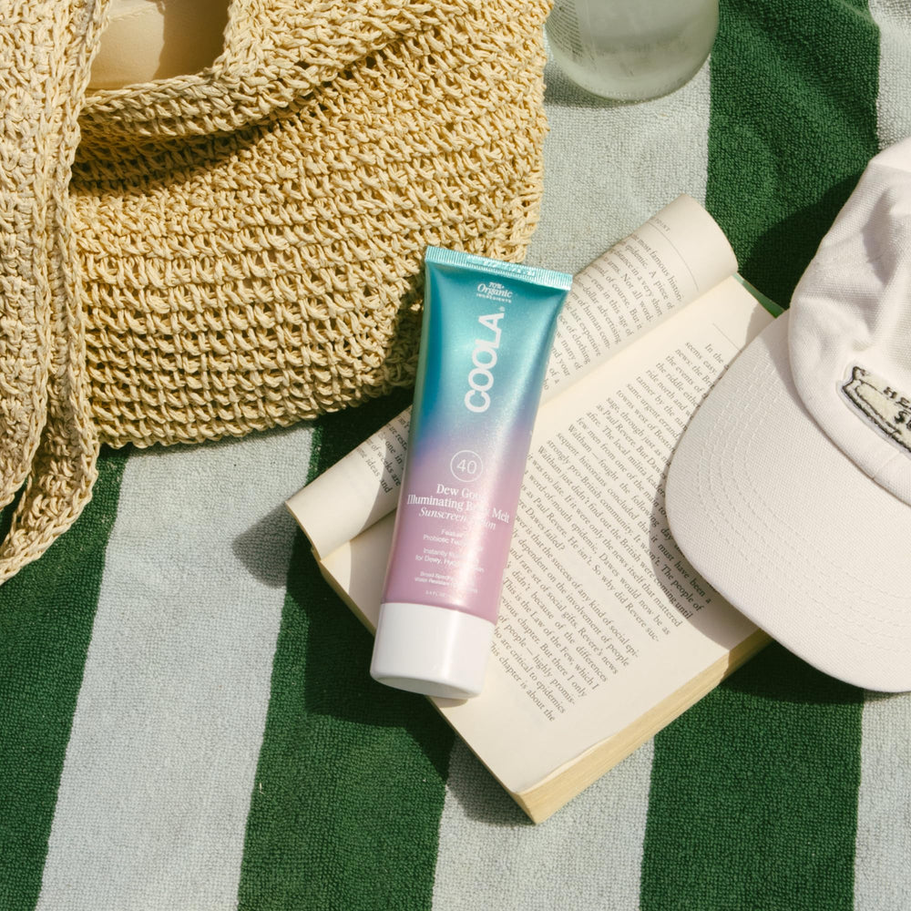 COOLA bottle on beach towel conveying outdoor use and sun-ready protection