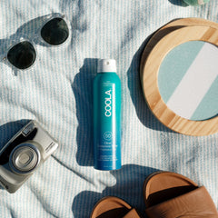 COOLA sunscreen spray being applied from bottle demonstrating easy reapplication