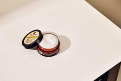 Duke Cannon tin on a nightstand indicating overnight skin repair use