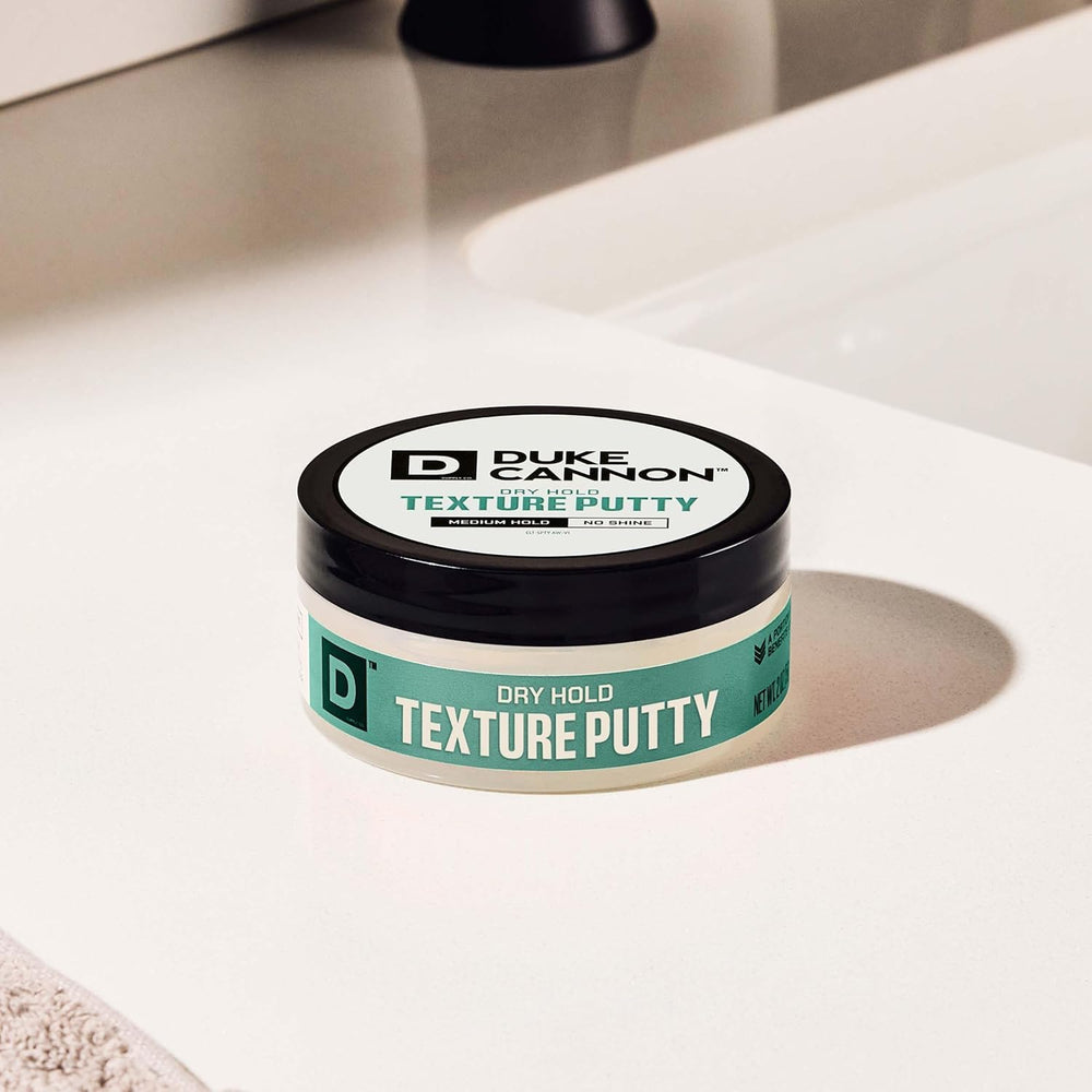 Hand scooping Duke Cannon putty to demonstrate easy application benefit