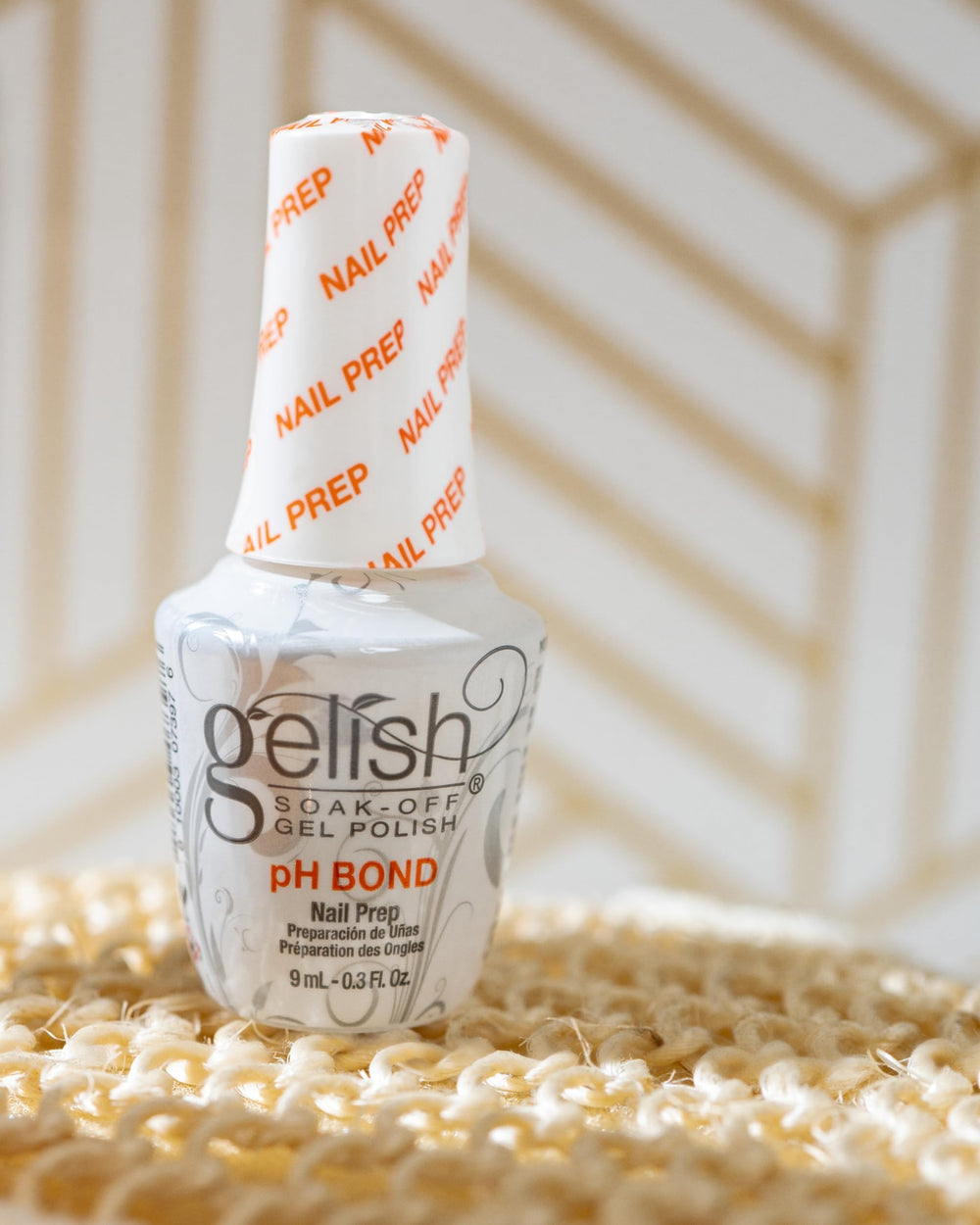 Hand holding Gelish MINI pH Bond to show scale and travel-friendly convenience