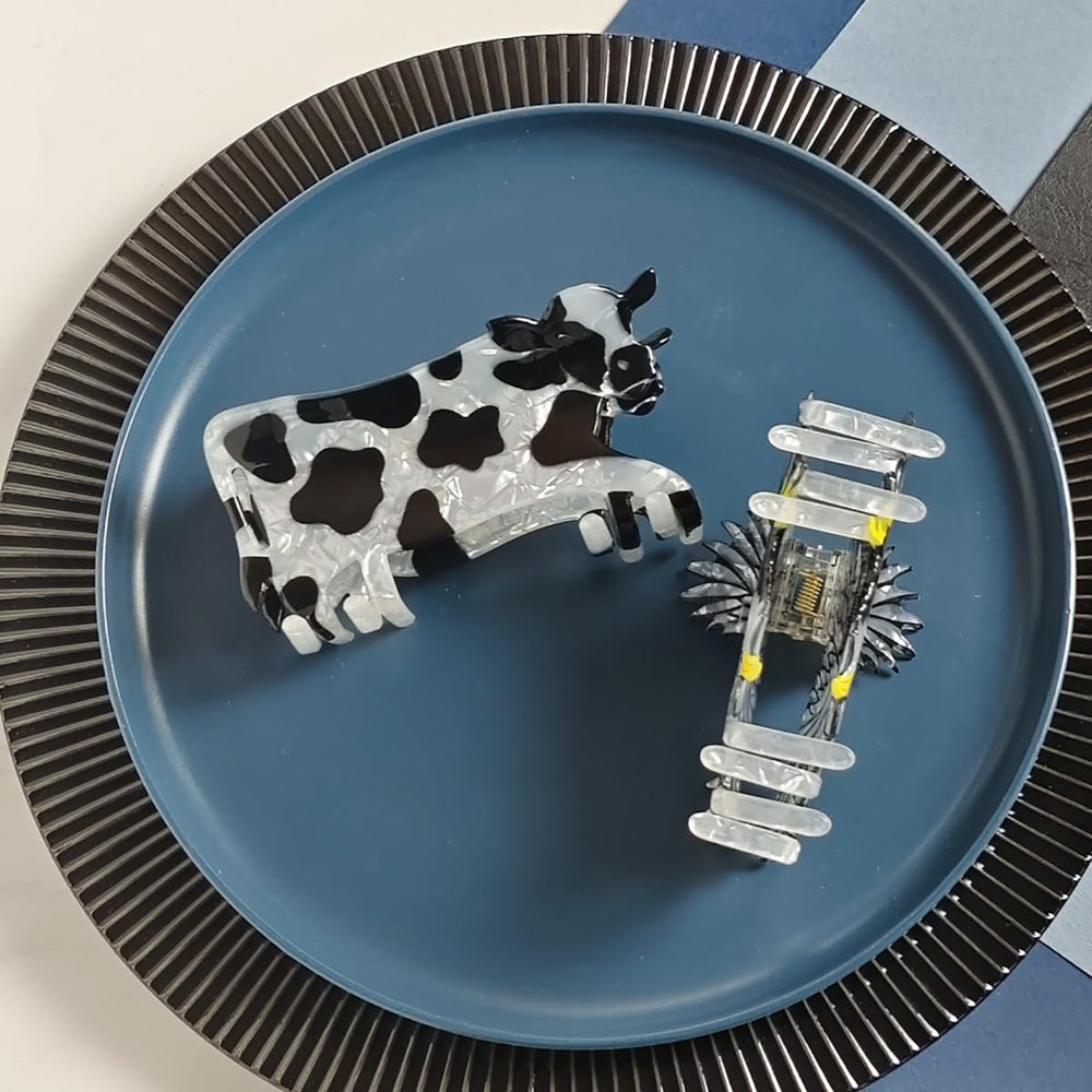 Generic cow clip beside hand for scale to show compact, portable size