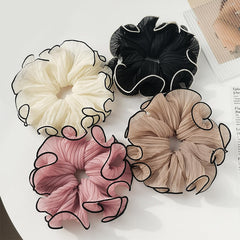 Generic scrunchies next to hand for size comparison, demonstrates roomy fit for thick hair