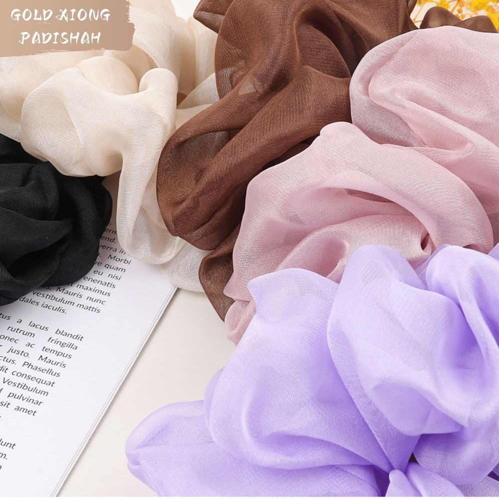 GOLD XIONG PADISHAH scrunchie next to hand to show oversized scale and volume