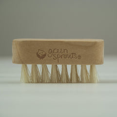 Green Sprouts brush held in adult hand over baby finger showing correct scale benefit