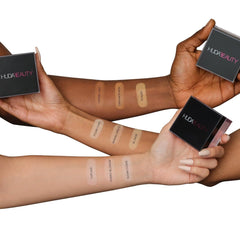 HUDA Beauty small scoop applying Cherry Blossom powder to target under-eye area