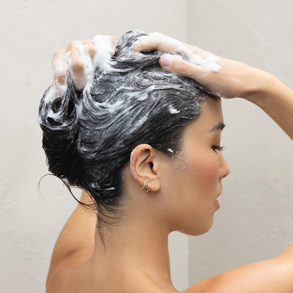 Kristin Ess shampoo pouring into hand for easy application benefit