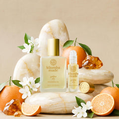 Kuumba Made bottle in sunlit garden scene showing warm floral-amber mood benefit