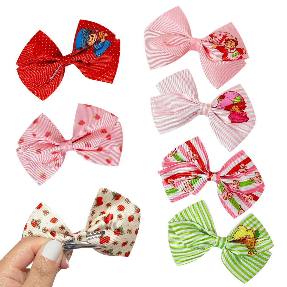 LUV HER seven bows laid out to display varied Strawberry Shortcake designs and colors
