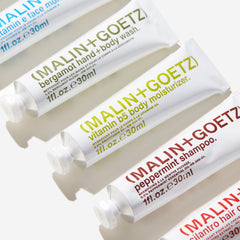 MALIN+GOETZ travel kit beside a passport to show TSA-friendly 1 oz scale
