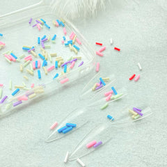 Mulutoo sprinkles next to a teaspoon, demonstrates compact quantity size