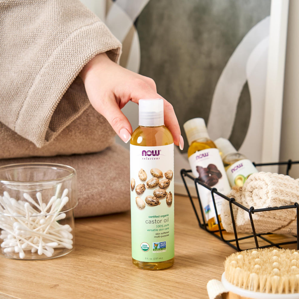 NOW Foods oil beside massage tools showing scalp massage prep and nourishment benefit