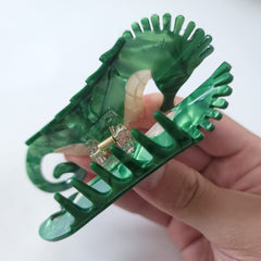 OMG Decor clip next to hand for scale showing compact, travel-friendly size
