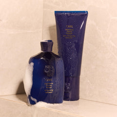 Oribe 6.8oz bottle next to a common object to show true size and travel-friendliness