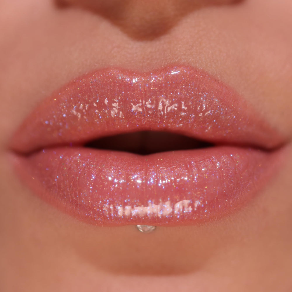 Revolution Pout Bomb texture swatch on skin demonstrating hydrating shimmer finish