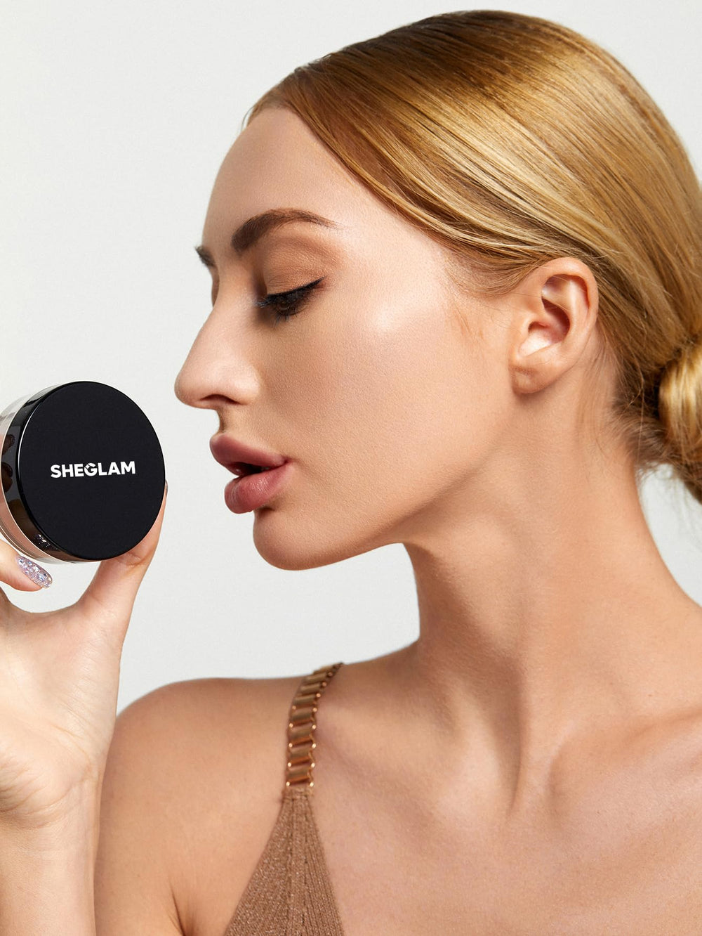 SHEGLAM powder container beside a coin for scale, illustrating compact travel-friendly size benefit