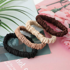 Srevela scrunchie beside a coin to show size and slim profile for travel convenience