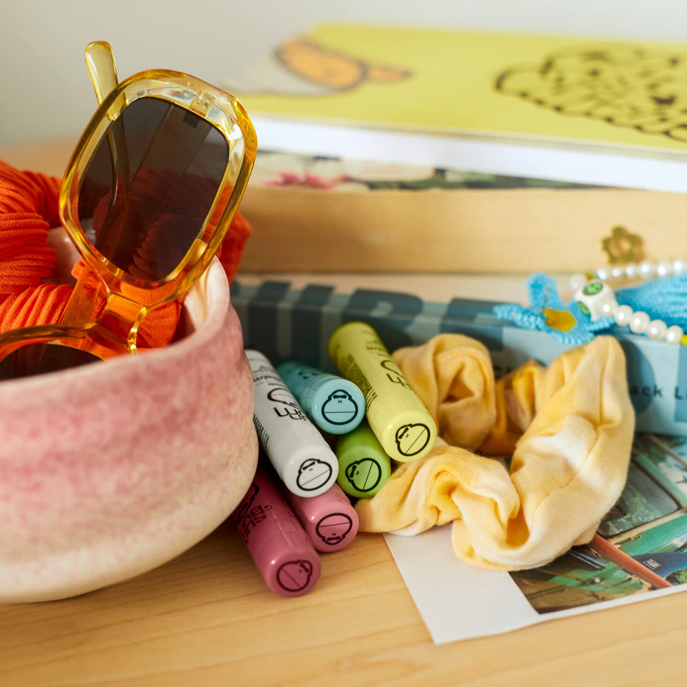 Sun Bum cocobalm next to a coin for size comparison showing compact tubes perfect for pockets and purses