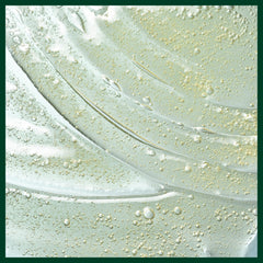 Aveda product next to plant extracts to emphasize mostly naturally derived ingredients