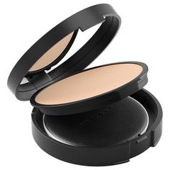 bareMinerals compact next to hand for scale showing travel-friendly size benefit