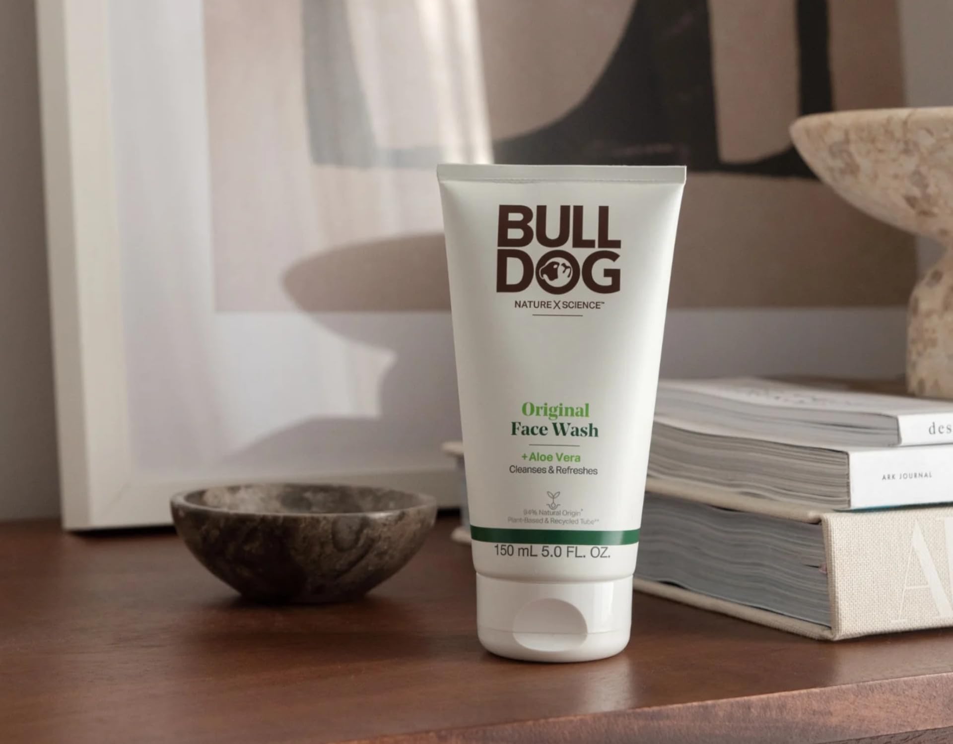 Bulldog Skincare bottle next to toiletries illustrating compact 5 oz size