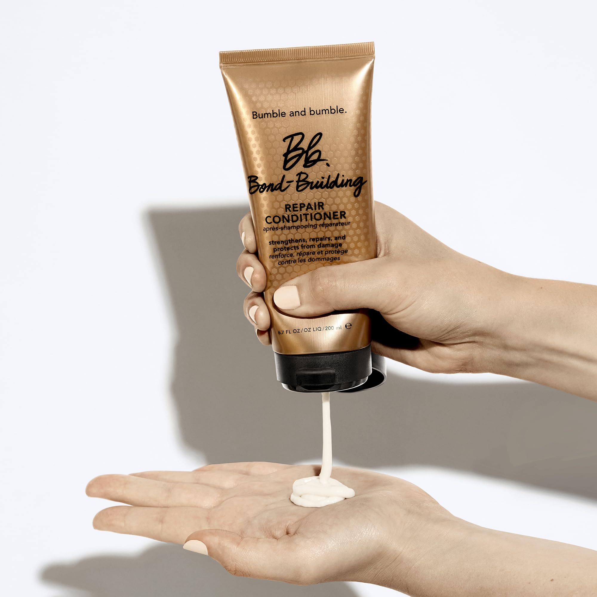 Bumble and bumble conditioner in hands demonstrating slip and spreadability