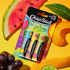 ChapStick by sunglasses on sand conveying travel-ready lip protection
