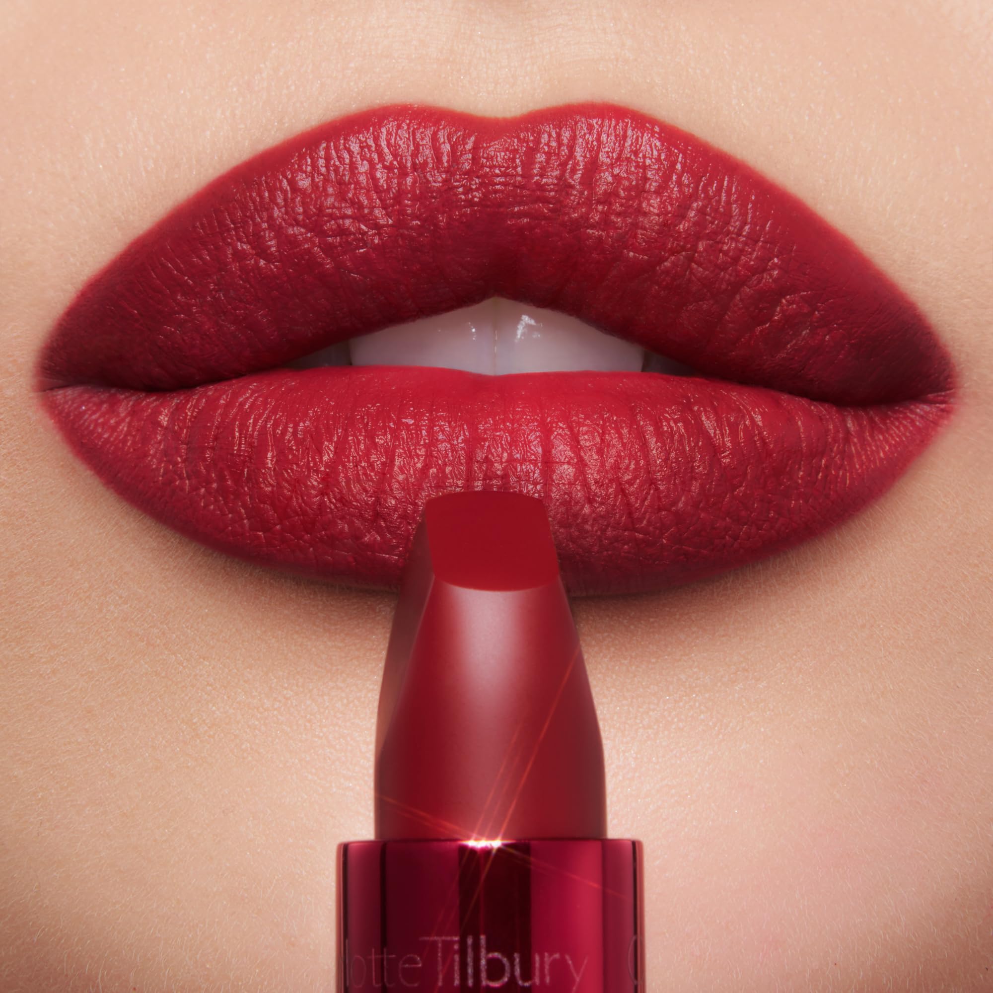 Charlotte Tilbury lip swatch on model highlighting bright cherry red vibrancy