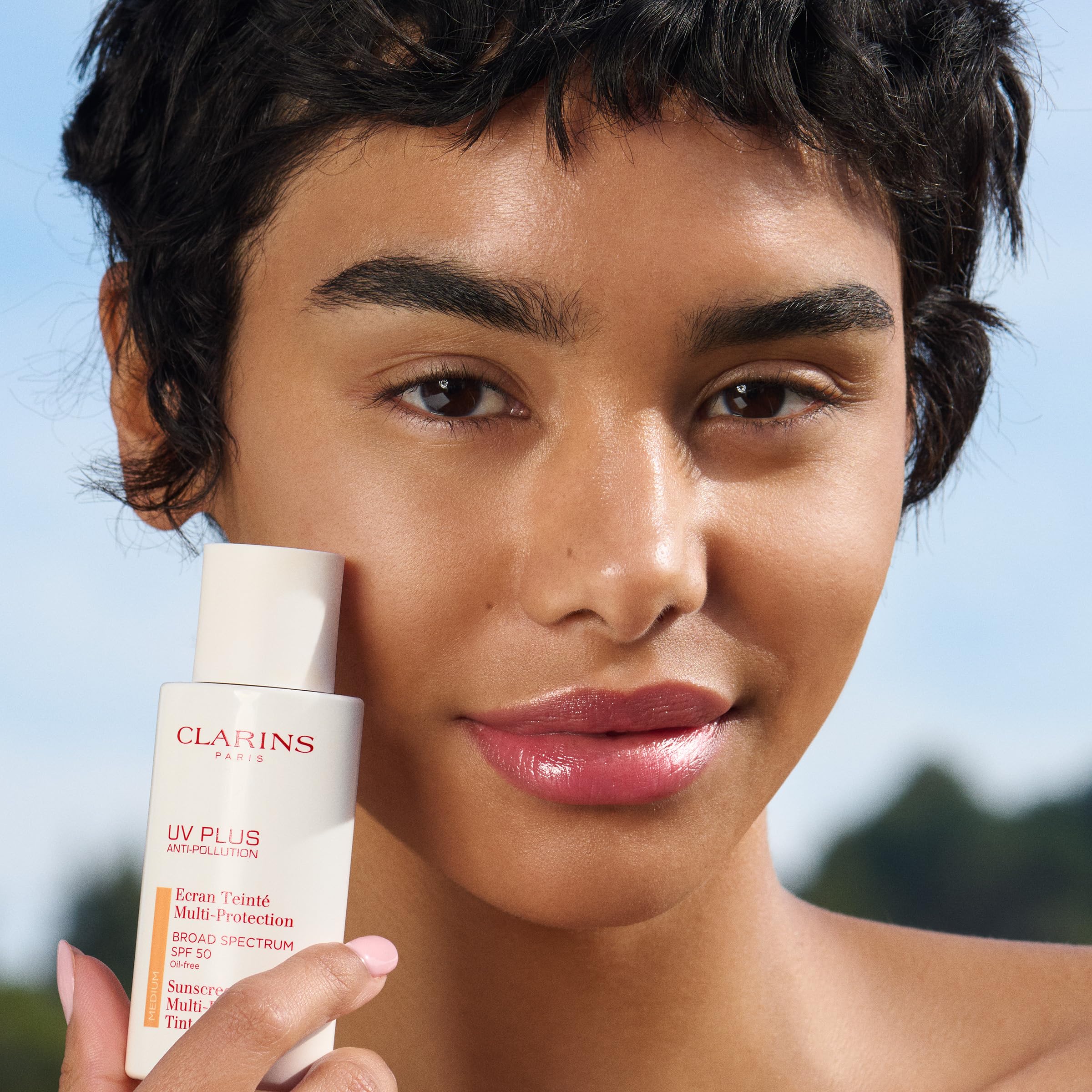 Clarins UV Plus tube in flatlay beside makeup items showing everyday routine benefit