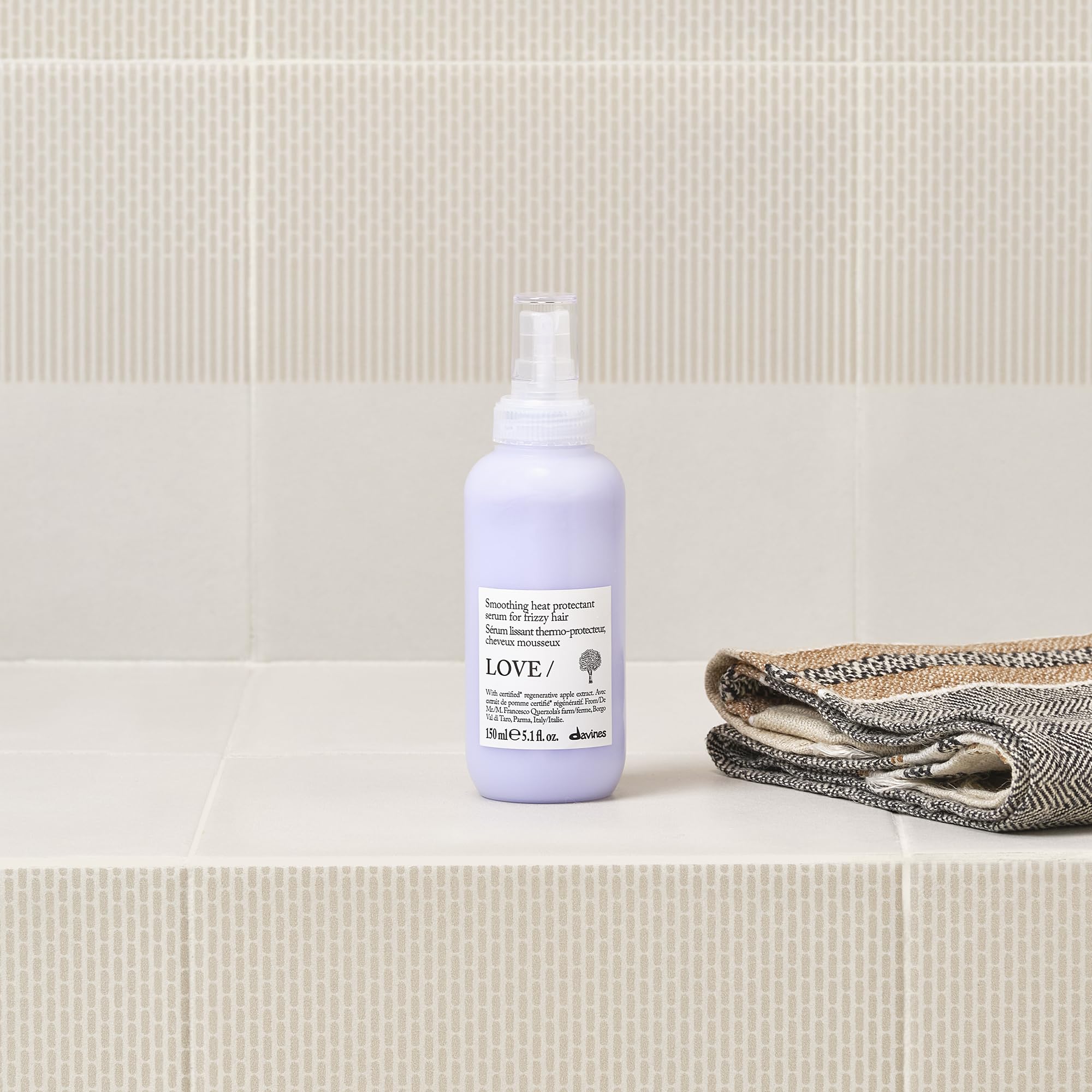Applying Davines serum to hands demonstrating frizz control benefit