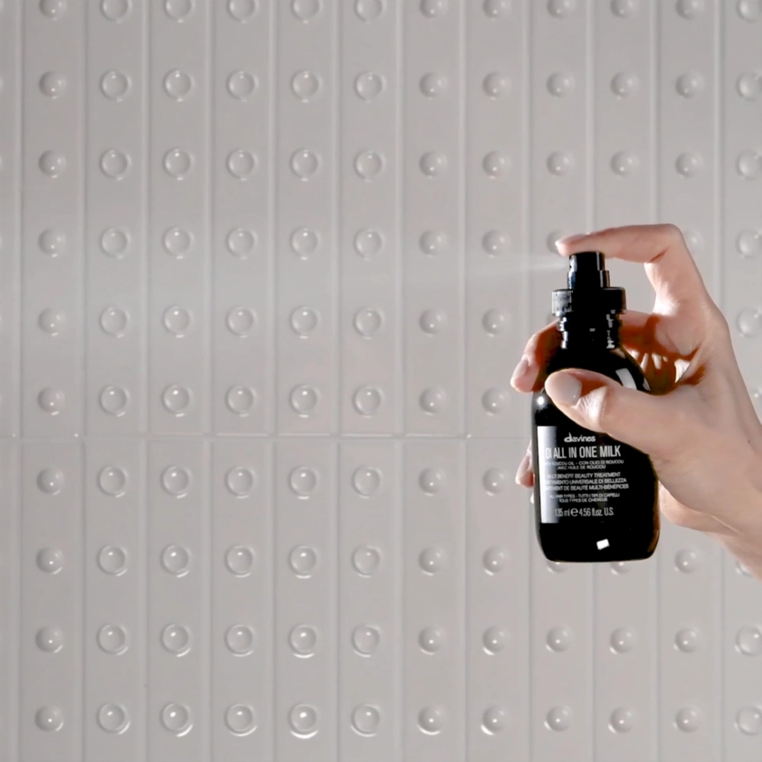 Hand holding Davines OI bottles to show true size and travel convenience