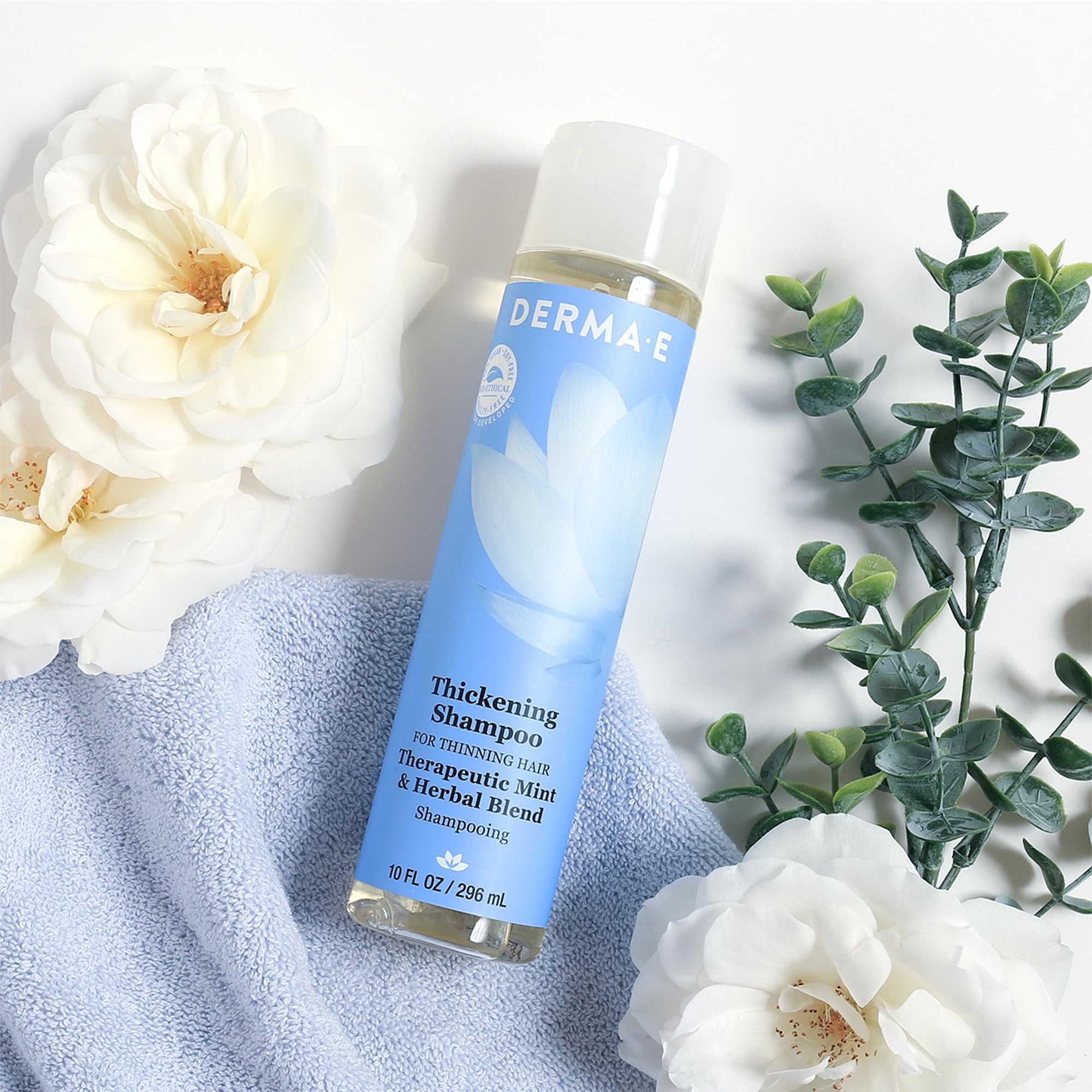 Derma E 10 oz shampoo in hand for size and travel-friendly scale