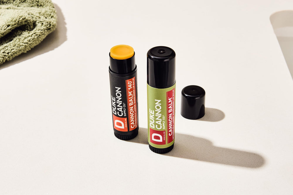 Duke Cannon blood orange balm in use outdoors on lips, provides sun protection during activity
