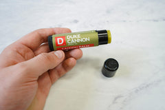 Duke Cannon beside standard chapstick illustrating larger 0.56oz tube value benefit