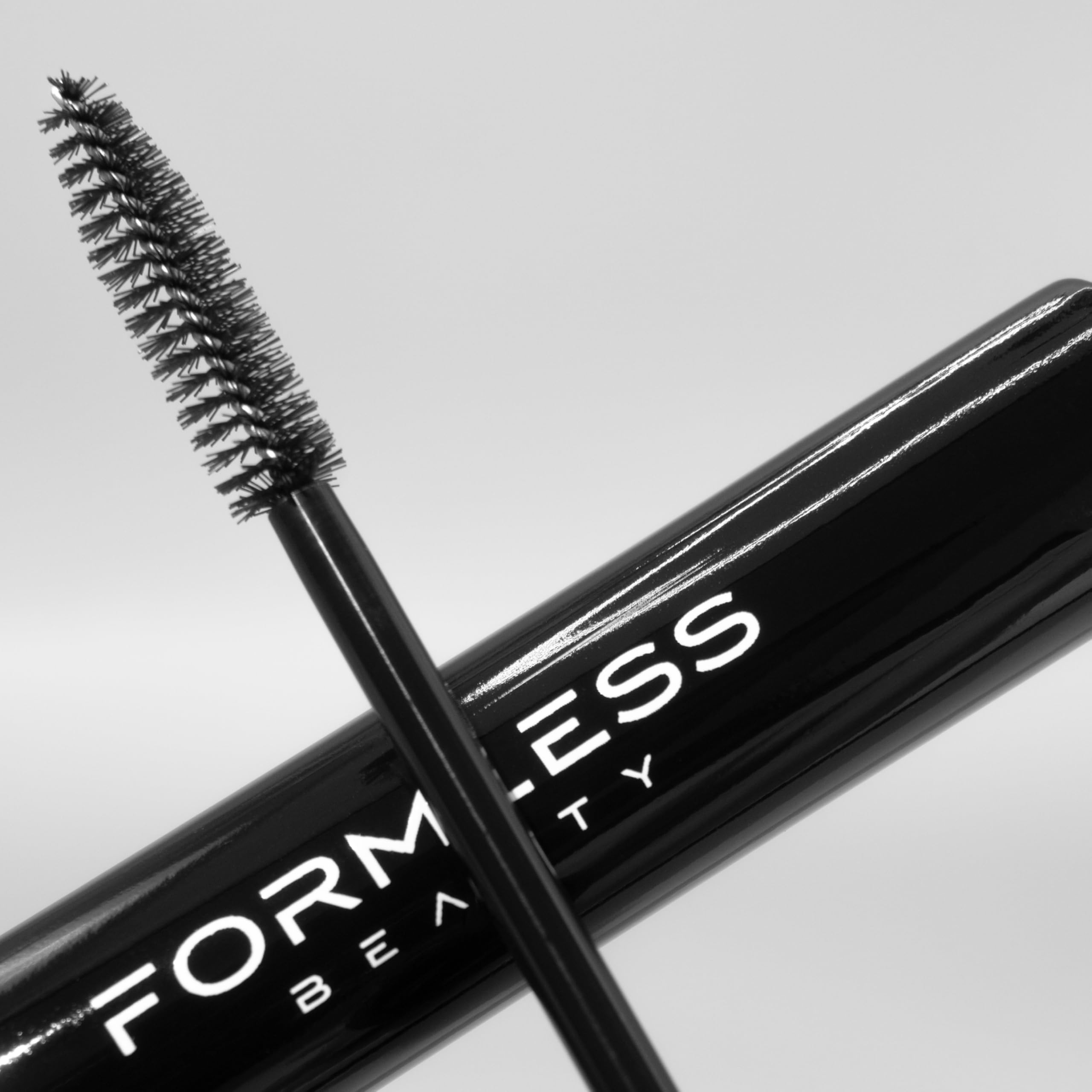 Model applying Formless Beauty Elevate Mascara to lashes showing lifted, voluminous finish