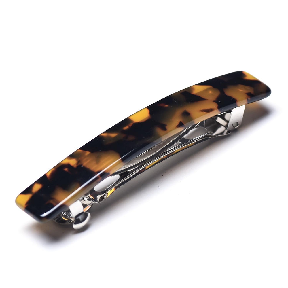 Fsmiling barrette held between fingers, illustrates lightweight, easy-to-use design