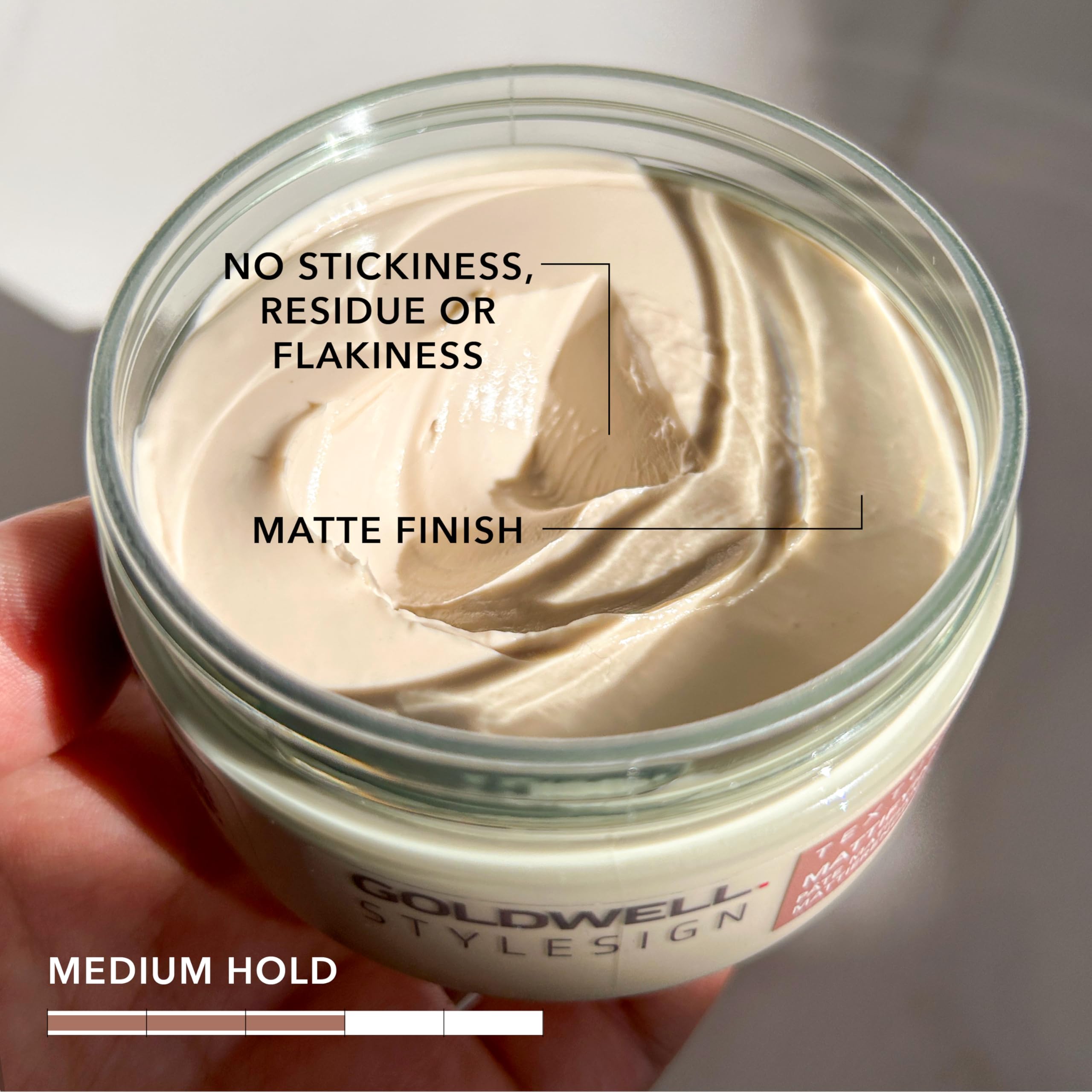 Hand applying Goldwell paste to hair for instant matte texture benefit