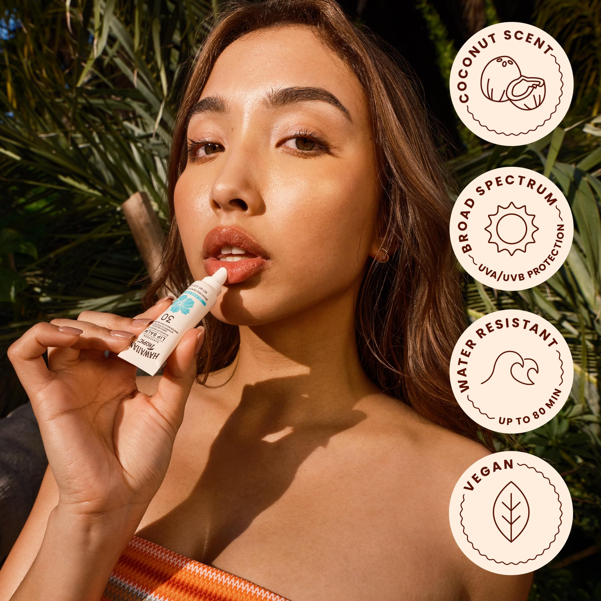 Hawaiian Tropic lip balm next to keys in hand for compact size benefit