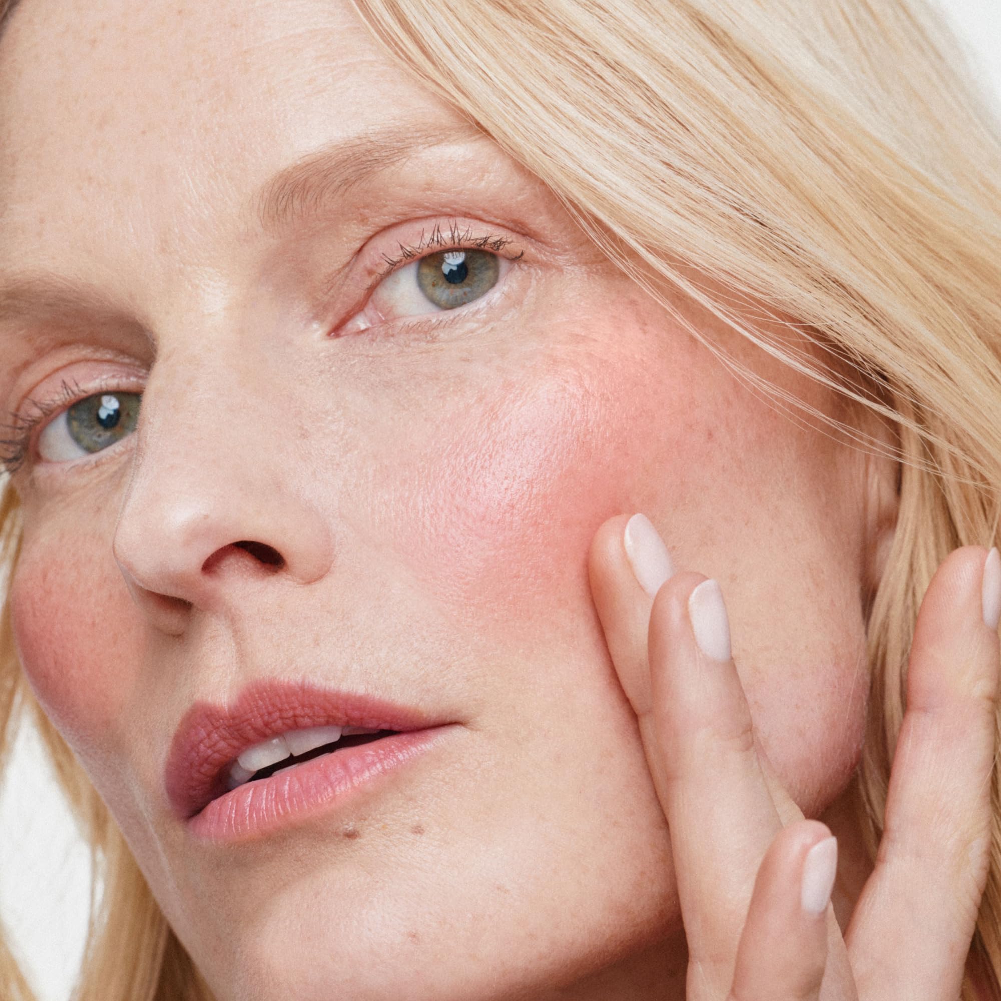 Applying ILIA Multi‑Stick Whisper to cheeks for natural luminescent flush and quick touchup
