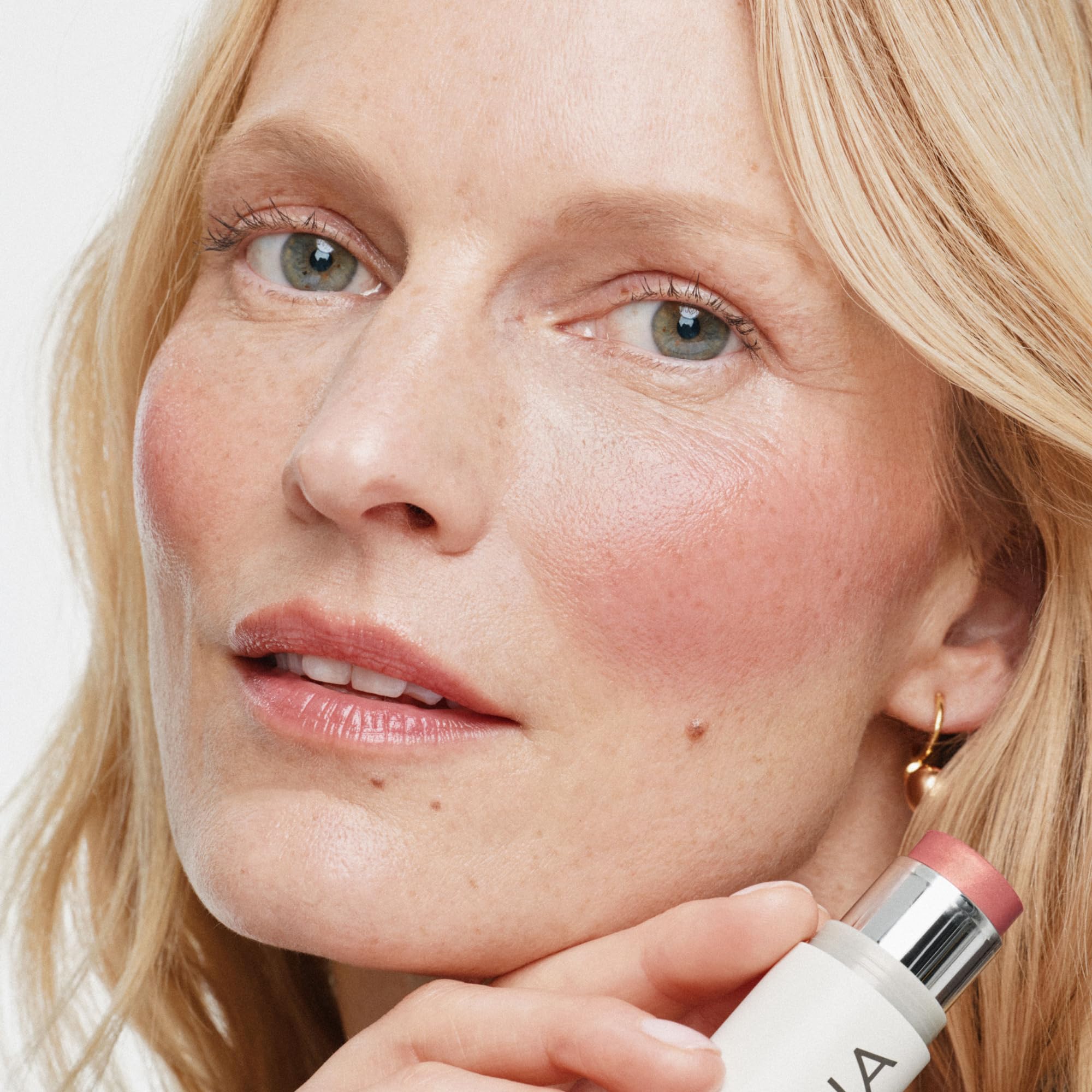ILIA applying to lips showing buildable color and soft sheen