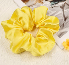 JGQUR scrunchie beside a coin to show extra-large size and volume fit