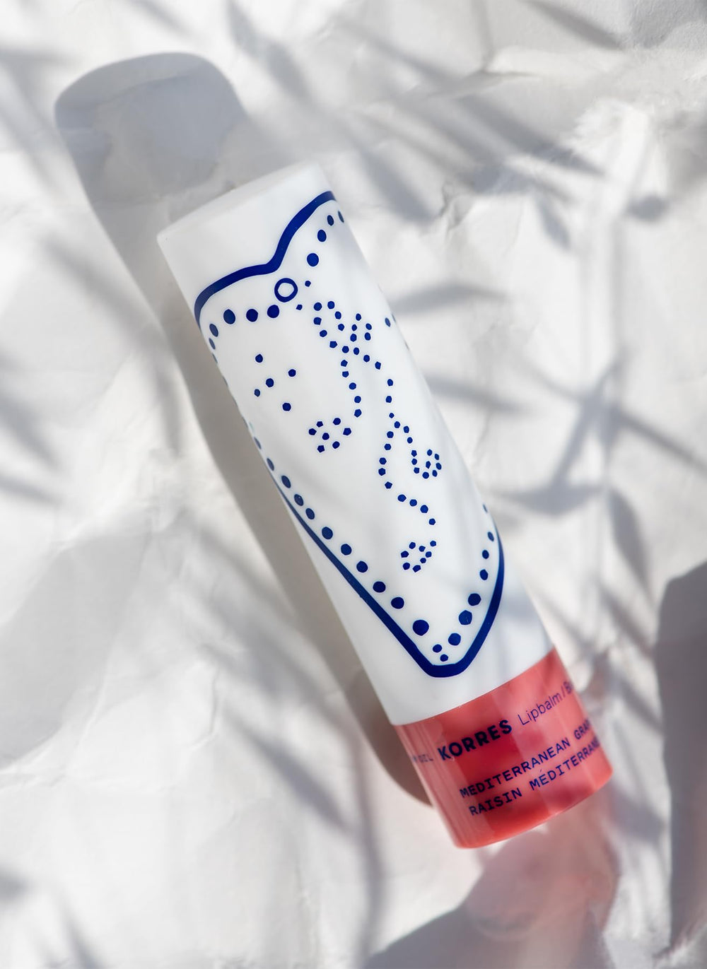 KORRES Lip Butter Stick next to coin showing compact travel-friendly size and portability